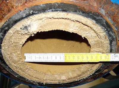 Close-up of a water pipe with a measuring tape showing diameter in inches.