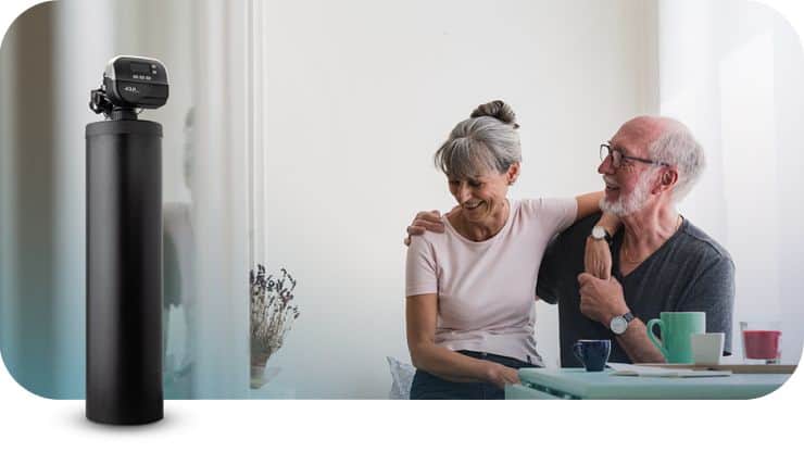 Water testing device on a black stand in a bright room with elderly couple smiling.