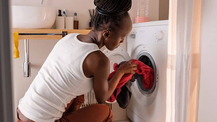 Woman loading laundry into a washing machine in a laundry room.