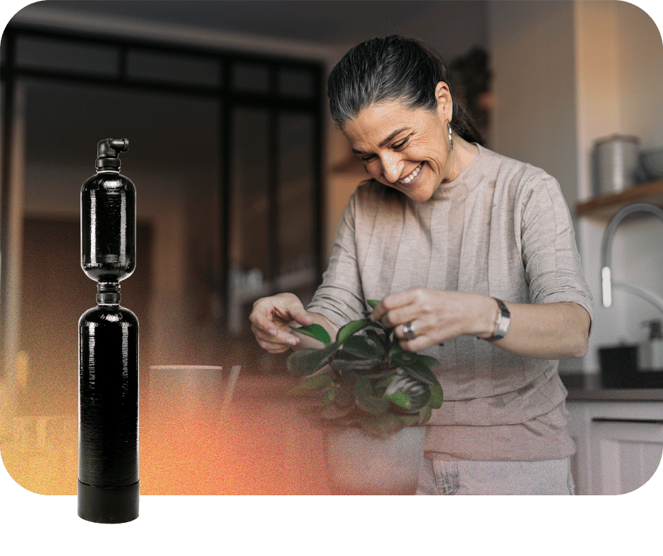 Woman smiling at a plant with a water testing device in the foreground.
