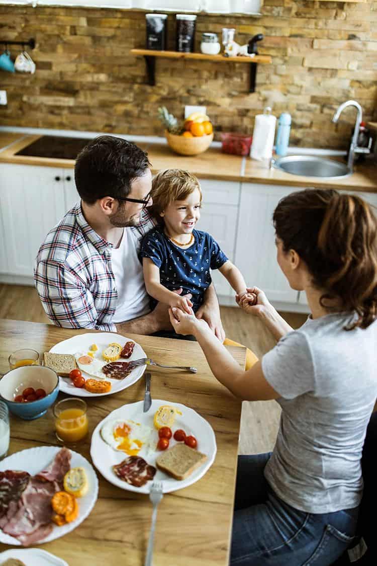 Family enjoying breakfast at kitchen table with water testing kit nearby.