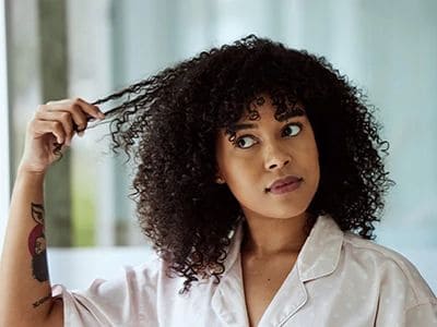 Young woman with curly hair touching her hair, indoors.