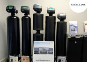 Commercial water treatment system with five black tanks and digital controllers in a business setting.