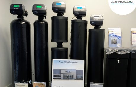 Commercial water treatment system with five black tanks and digital controllers in a business setting.
