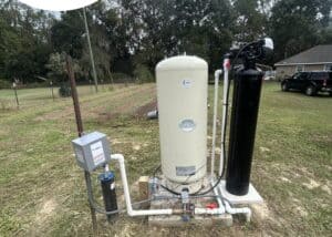 Water treatment system installed outdoors with tanks and filtration units in a grassy area.