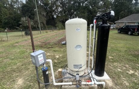 Water treatment system installed outdoors with tanks and filtration units in a grassy area.